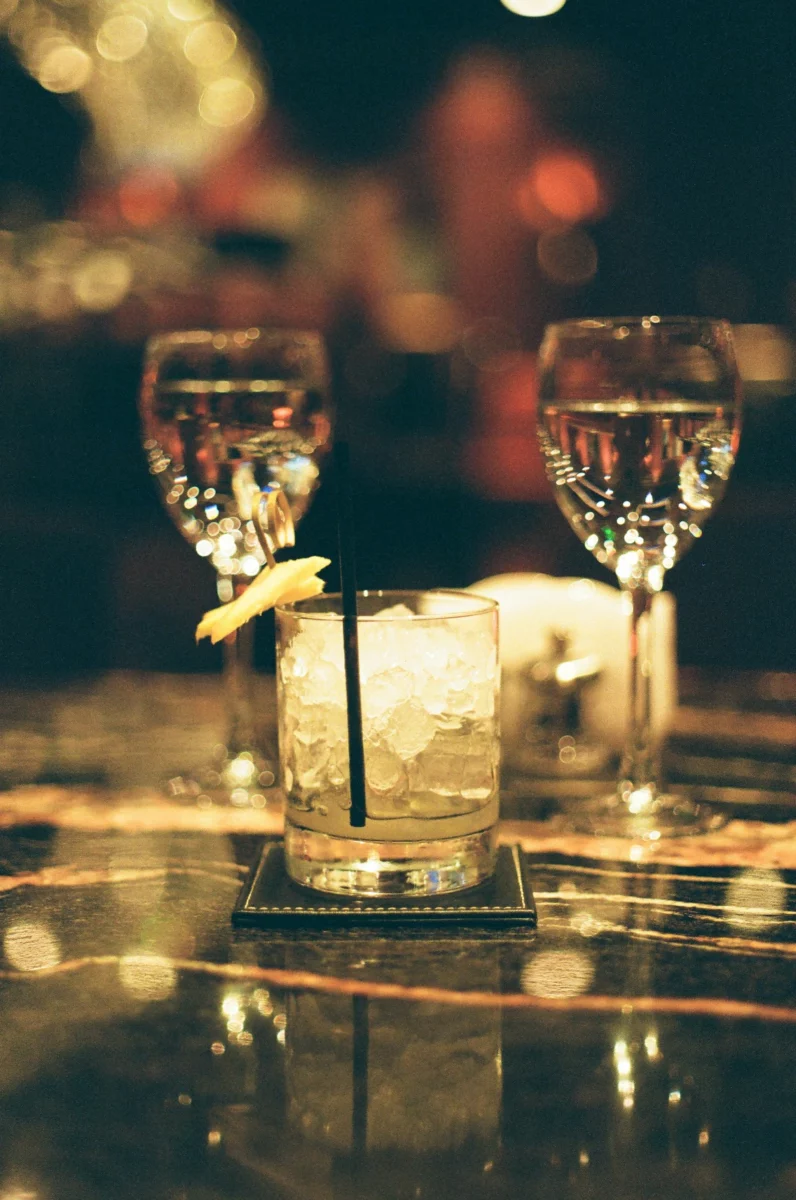 Verre avec glaçons posé près de verres à vin sur un comptoir, illustrant la question du diabète et de l'alcool