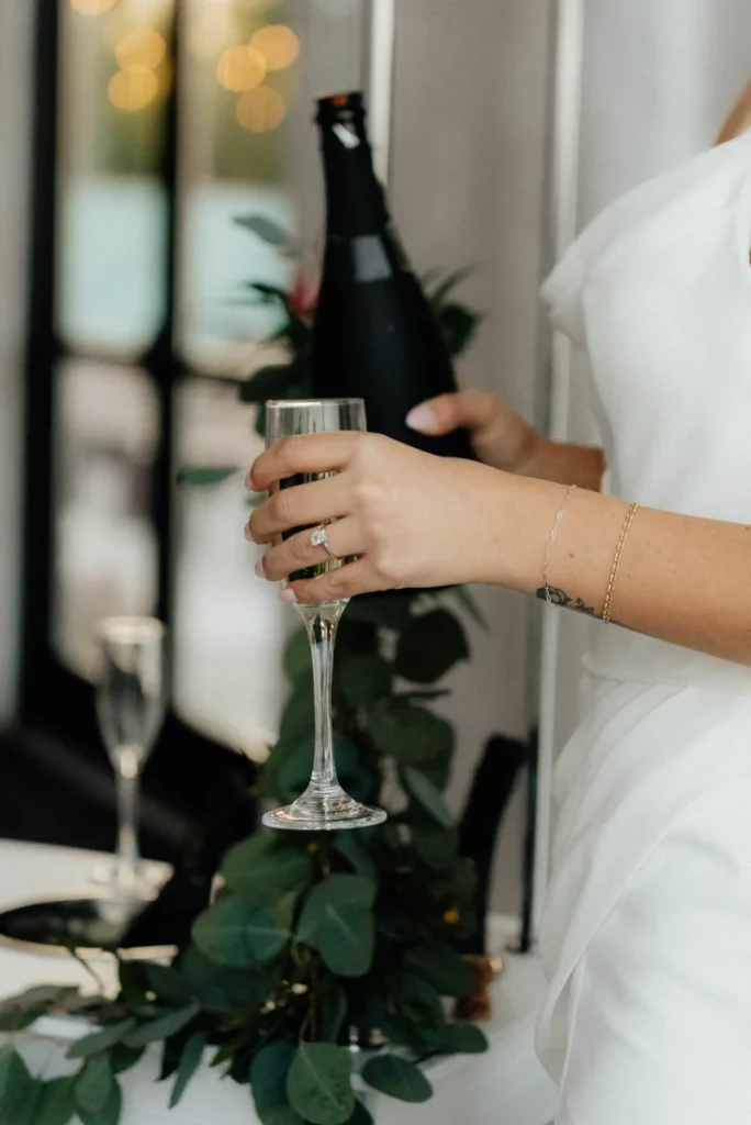Mariée tenant une coupe et une bouteille de champagne