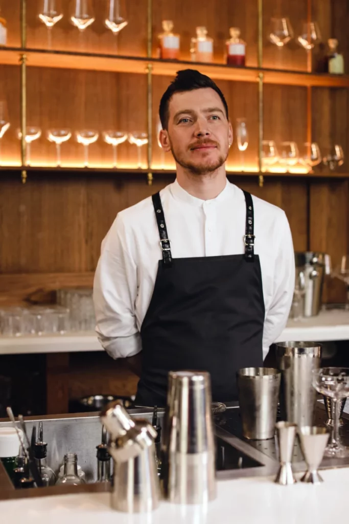 Barman professionnel derrière son comptoir, illustration de la formation barmen Horeca à Bruxelles