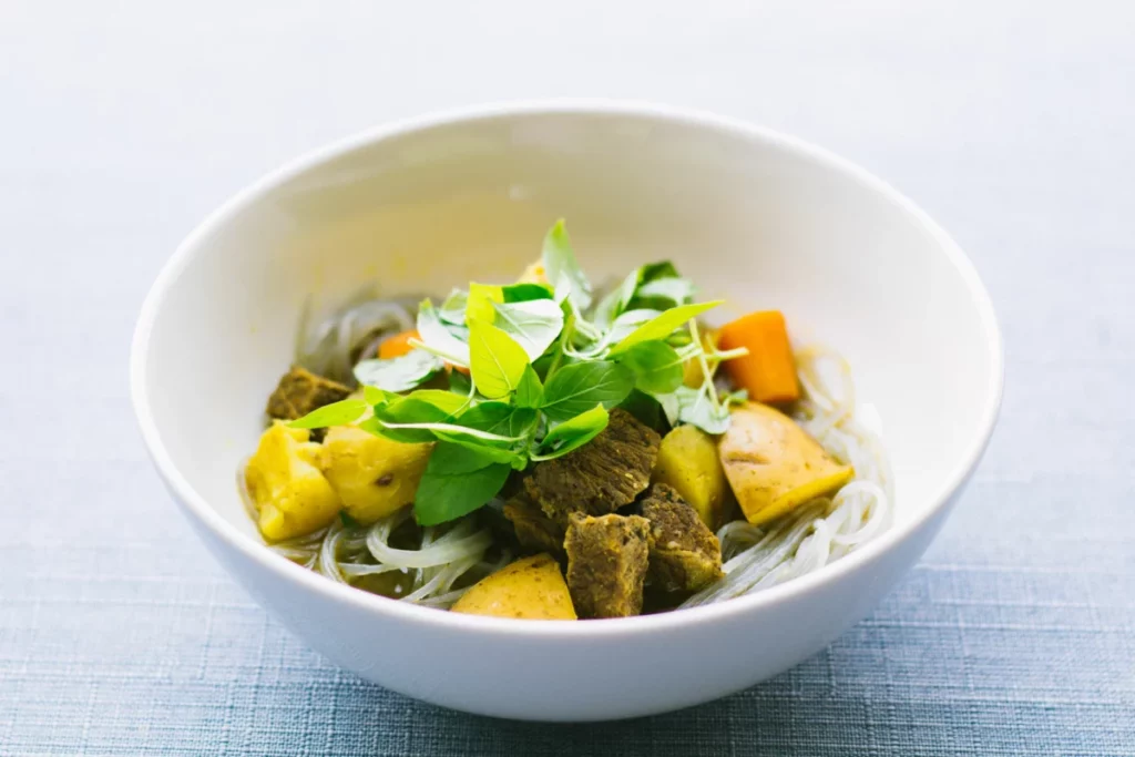 Bol de soupe vietnamienne garnie d'herbes fraîches, cuisine servie à L'Orchidée Blanche à Bruxelles