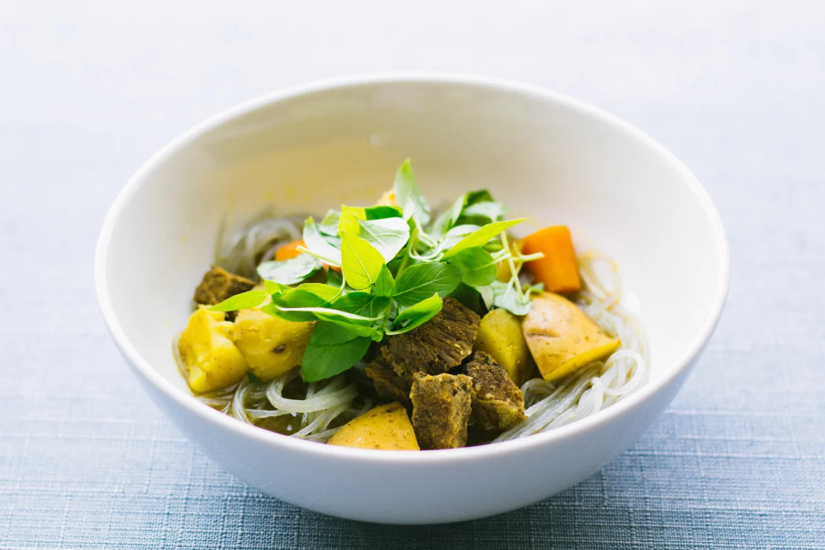 Bol de soupe vietnamienne garnie d'herbes fraîches, cuisine servie à L'Orchidée Blanche à Bruxelles