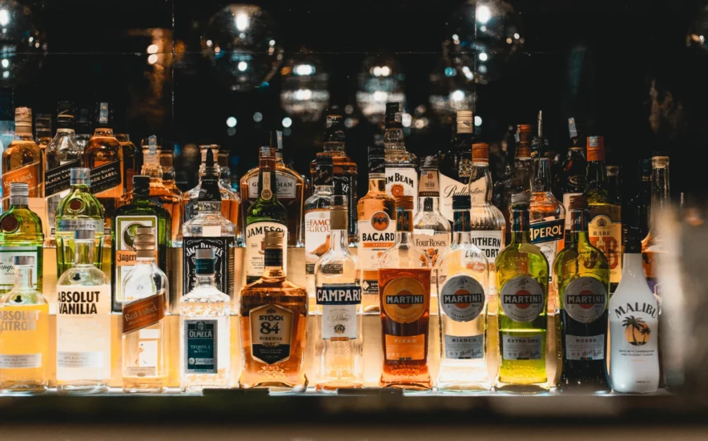 Bouteilles de liqueurs alignées sur une étagère de bar illuminée, comme les liqueurs Giffard
