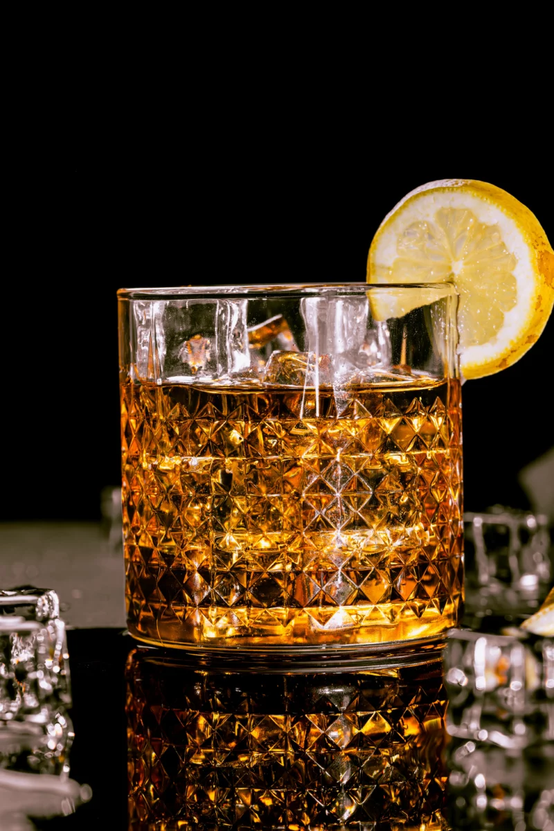 Verre de whisky avec une tranche de citron posé sur un comptoir, servi comme un Bourbon Renewal