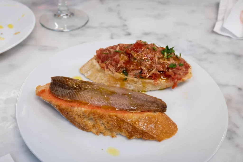 Assortiment de tapas et de conserves de poisson sur marbre, illustration de l'accord anchois et vin