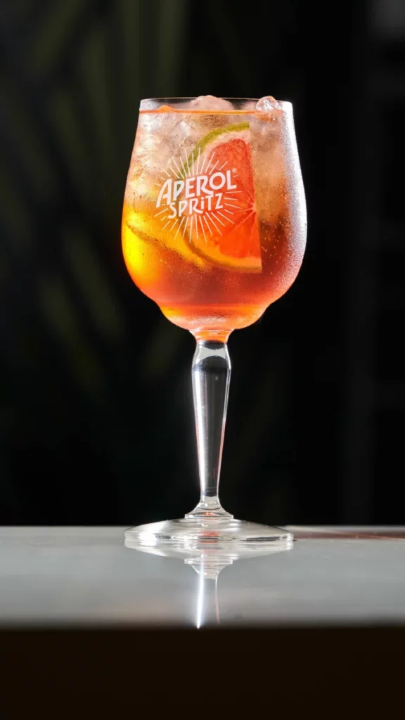 Verre de spritz orangé avec tranche d'orange sur une table, dans l'esprit du Lillet Rosé Spritz des 150 ans