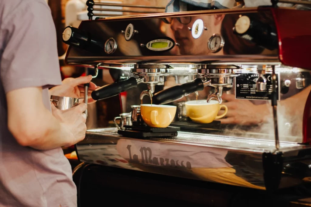 Barista utilisant une machine à café professionnelle derrière le comptoir d'un café