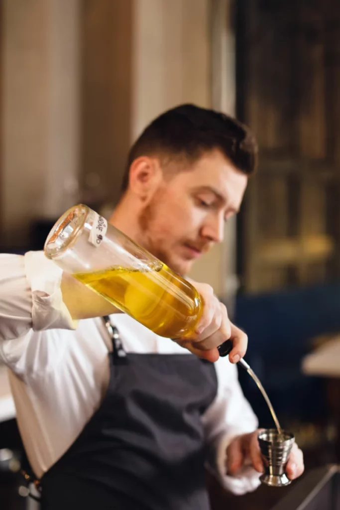 Barman versant un alcool dans un jigger de mesure