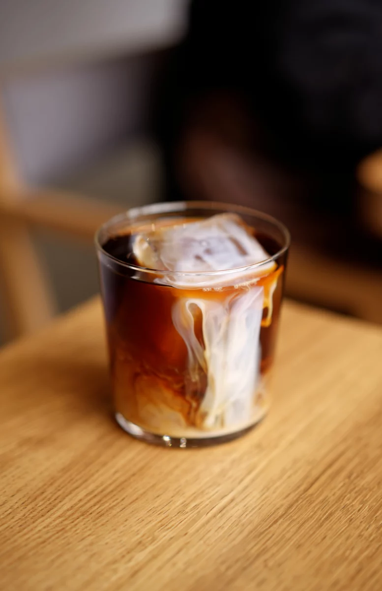 Verre de caffè shakerato glacé avec sa mousse de café sur une table en bois
