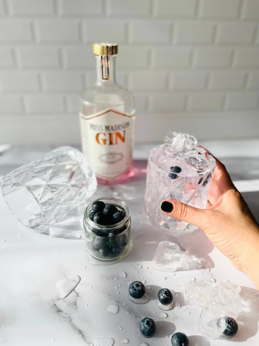 Main tenant un verre de gin tonic avec glaçons, pour illustrer le meilleur tonic pour gin