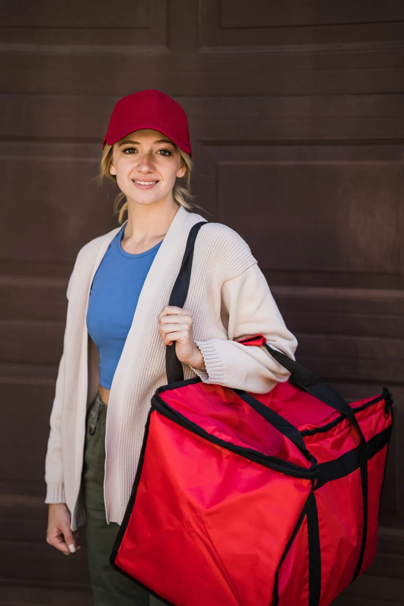 Livreuse portant un sac isotherme de livraison de repas, service comparable à Deliveroo Signature Service