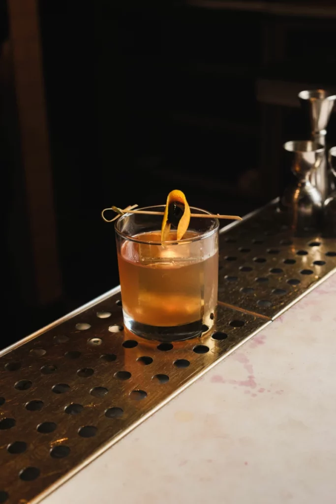 Livre ouvert posé à côté d'un verre de cocktail ambré, atmosphère roman policier