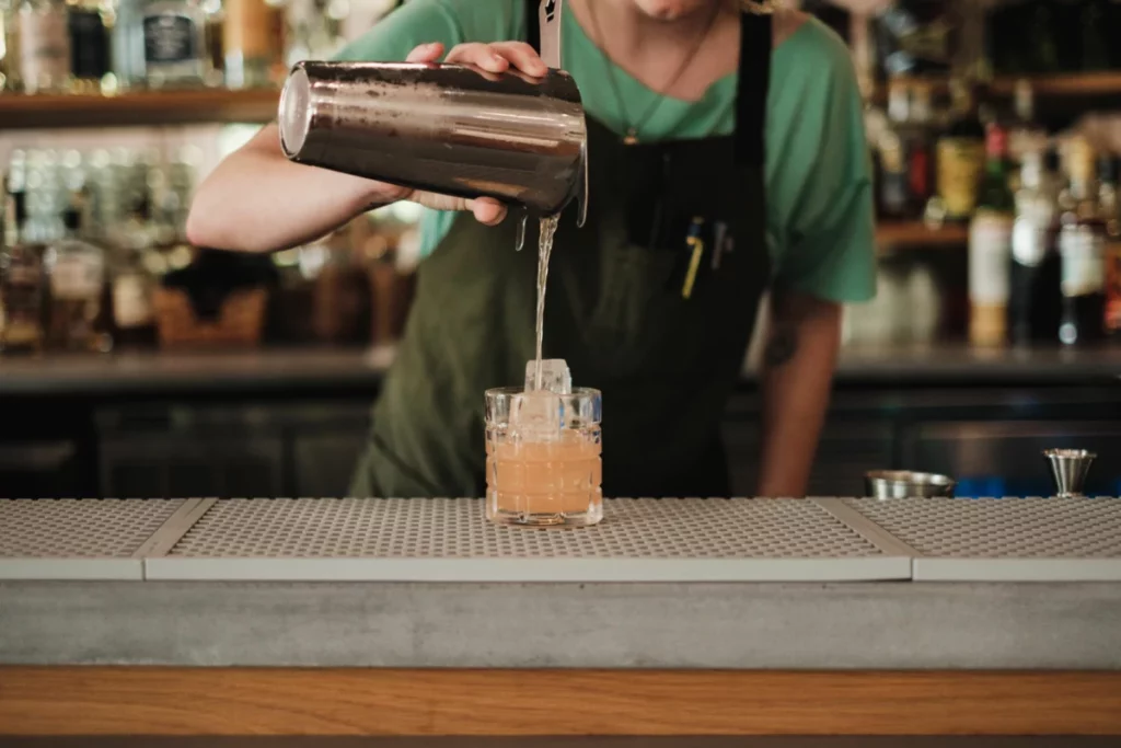 Bartender préparant un cocktail derrière un comptoir, dans l'esprit de Tales of the Cocktail 2022