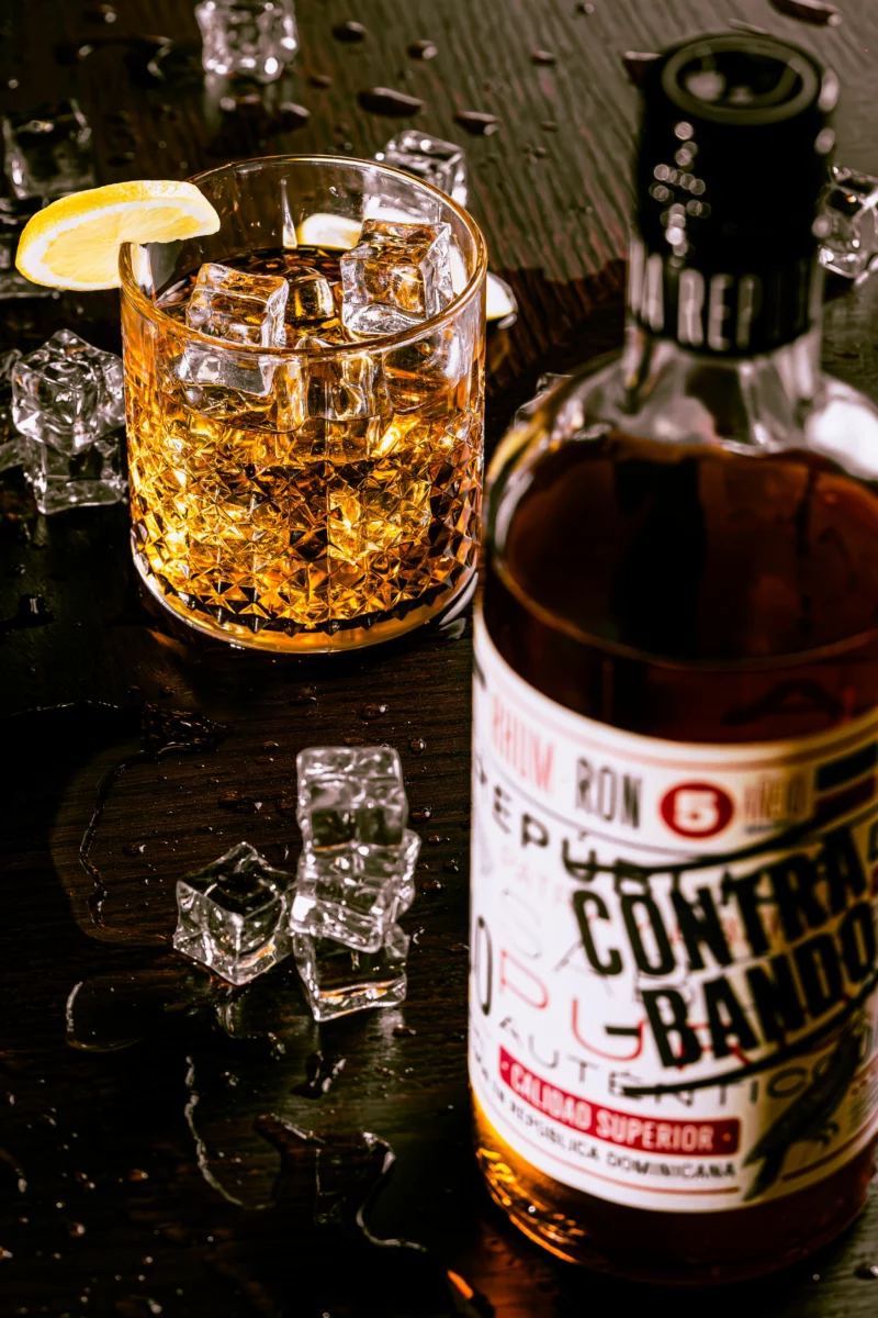 Bouteille et verre de rhum agricole avec glaçons, sujet du finish en fût d'acacia