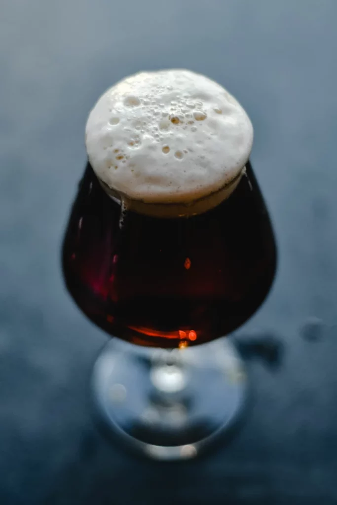 Verre de bière brune servi avec une mousse dense
