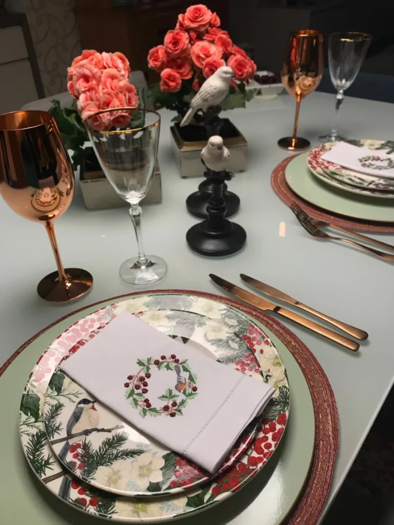 Table de restaurant gastronomique dressée avec assiettes fleuries et verres à vin