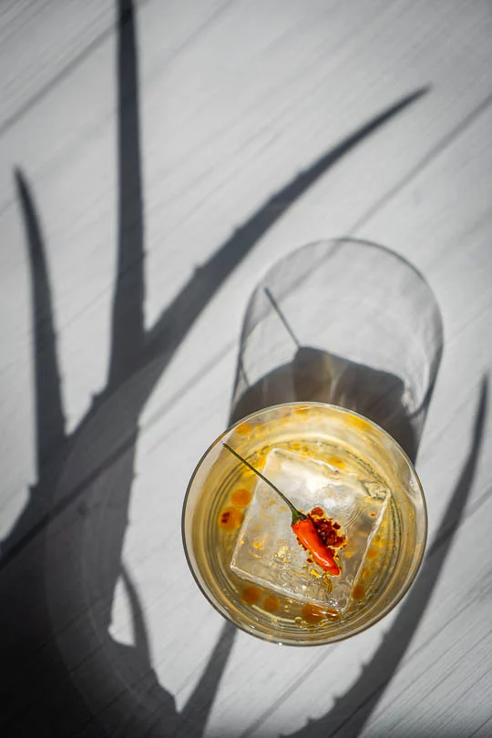 Old Fashioned tequila garni d'huile pimentée et de flocons de piment sur un gros glaçon