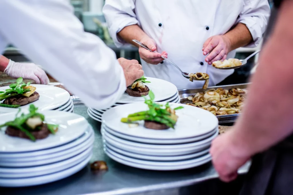 Cuisiniers dressant des assiettes en cuisine professionnelle pour un menu estival au restaurant