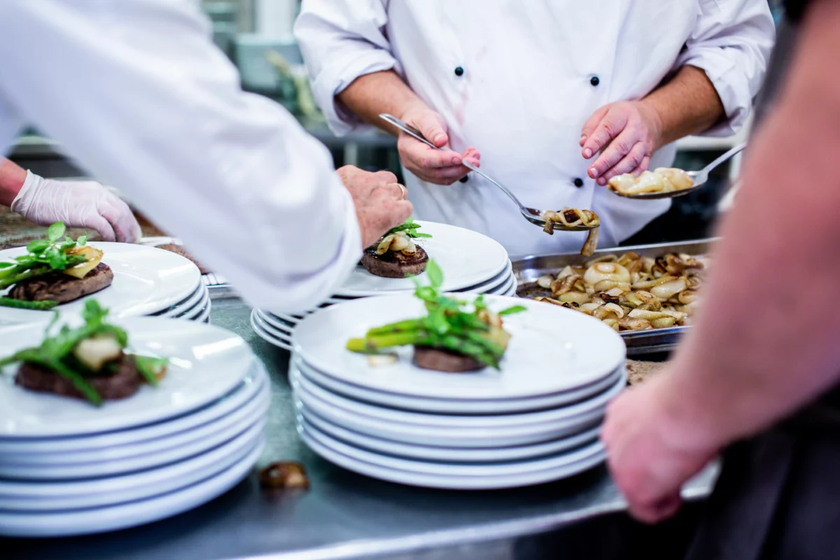 Cuisiniers dressant des assiettes en cuisine professionnelle pour un menu estival au restaurant