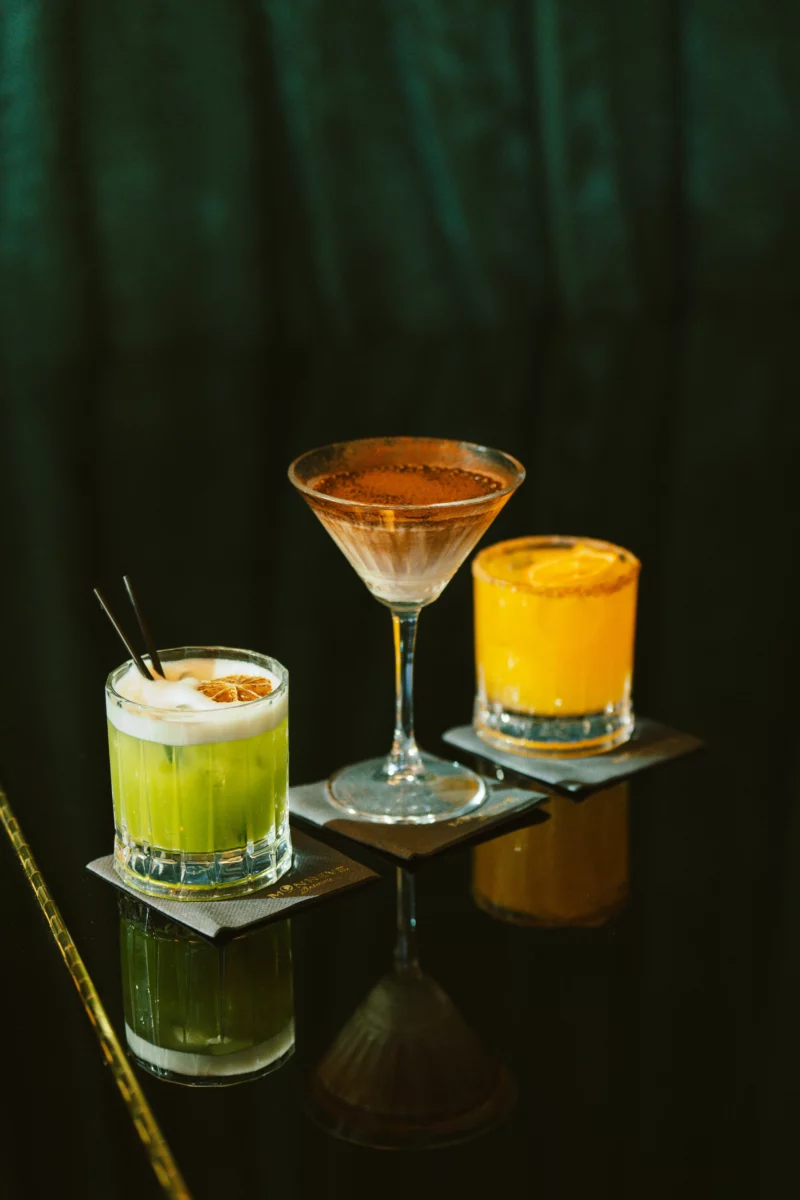 Cocktails colorés alignés sur une table noire, dans l'esprit du gin fizz fleur de sureau
