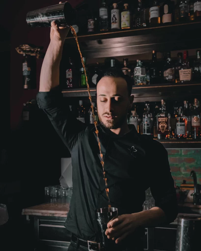 Bartender préparant un cocktail derrière un comptoir, en écho au parcours de Lauren Paylor