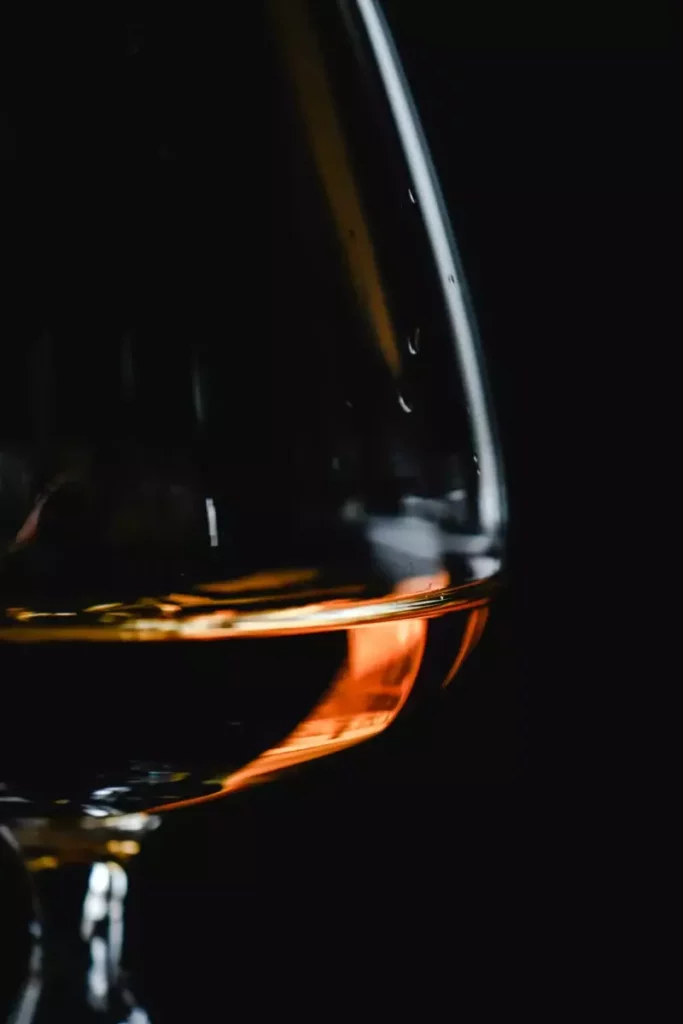 Verre ambré sur fond sombre illustrant le cocktail Sherry Darling au brandy de pomme