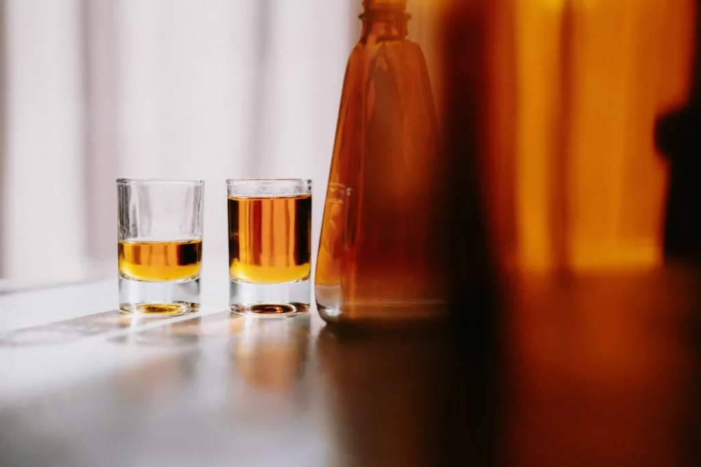 Deux verres de whisky ambré sur une table ensoleillée, où se révèle l'arôme de mangue du whisky