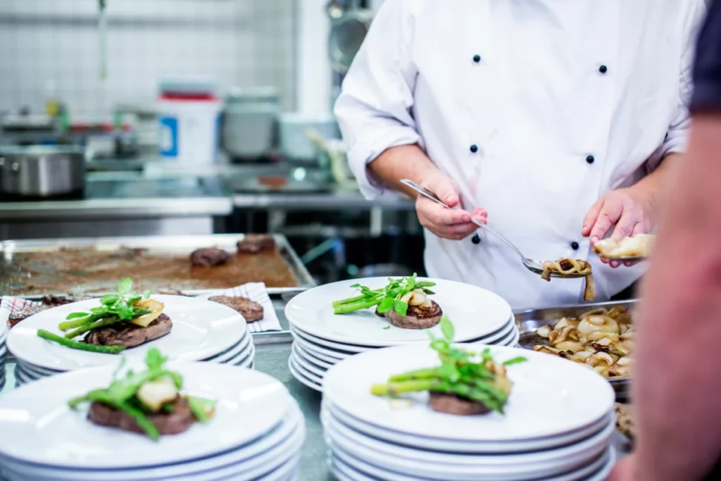 Chef italien en veste blanche préparant un plat, illustrant le savoir-faire de l’ACIB en Belgique