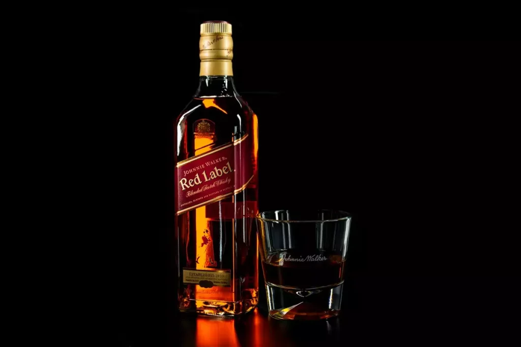 Bouteille et verre de whisky écossais dans une lumière ambrée, en écho à la Macallan noix de coco