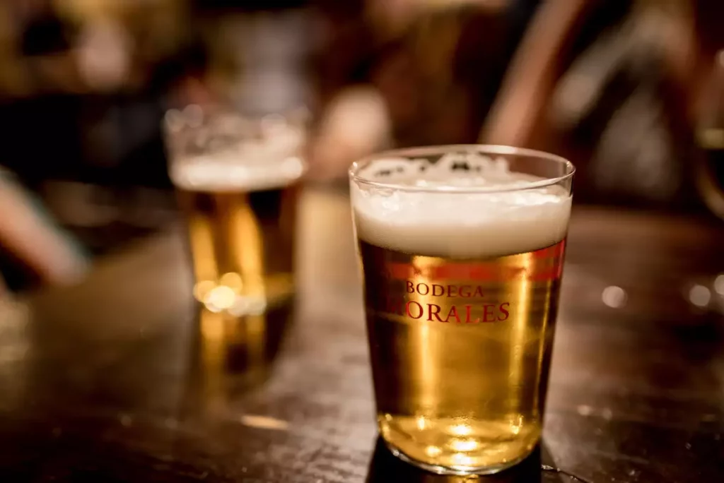 Deux verres de bière brune trappiste posés sur une table en bois, en écho au centenaire de la Westmalle Dubbel