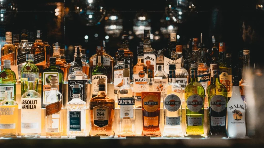 Bouteilles d'alcool alignées sur une étagère de bar illuminée, illustrant l'actu boissons de la semaine du 31 août