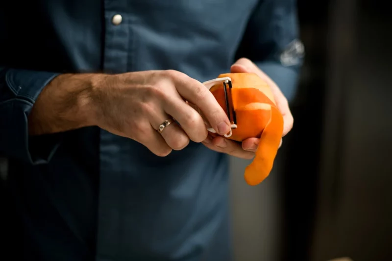 homme épluchant une orange